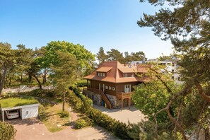 En toetages bygning med saddeltag, en overdækket veranda og en carport.