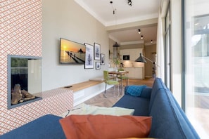 En moderne stue med en blå sofa, pejs og spiseplads med et bord og stole.