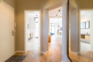 A modern interior with a wooden floor, a reception area, and a dining space visible through an open door. - Villa Bellevue, App. 04 (Heringsdorf)