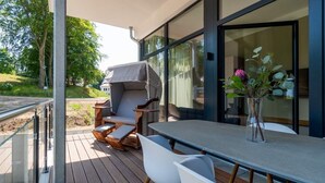 En udendørs terrasse med bord og stole, en fletstol og en grill.