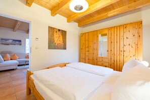 Une chambre avec un lit en bois, une armoire en bois et un tableau accroché au mur.