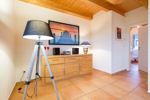 Une pièce avec un plafond en bois, un bureau avec une lampe, un grand tableau et un meuble.