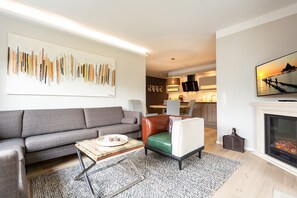A modern living room with a grey sofa, a green and white armchair, a coffee table, and a fireplace.