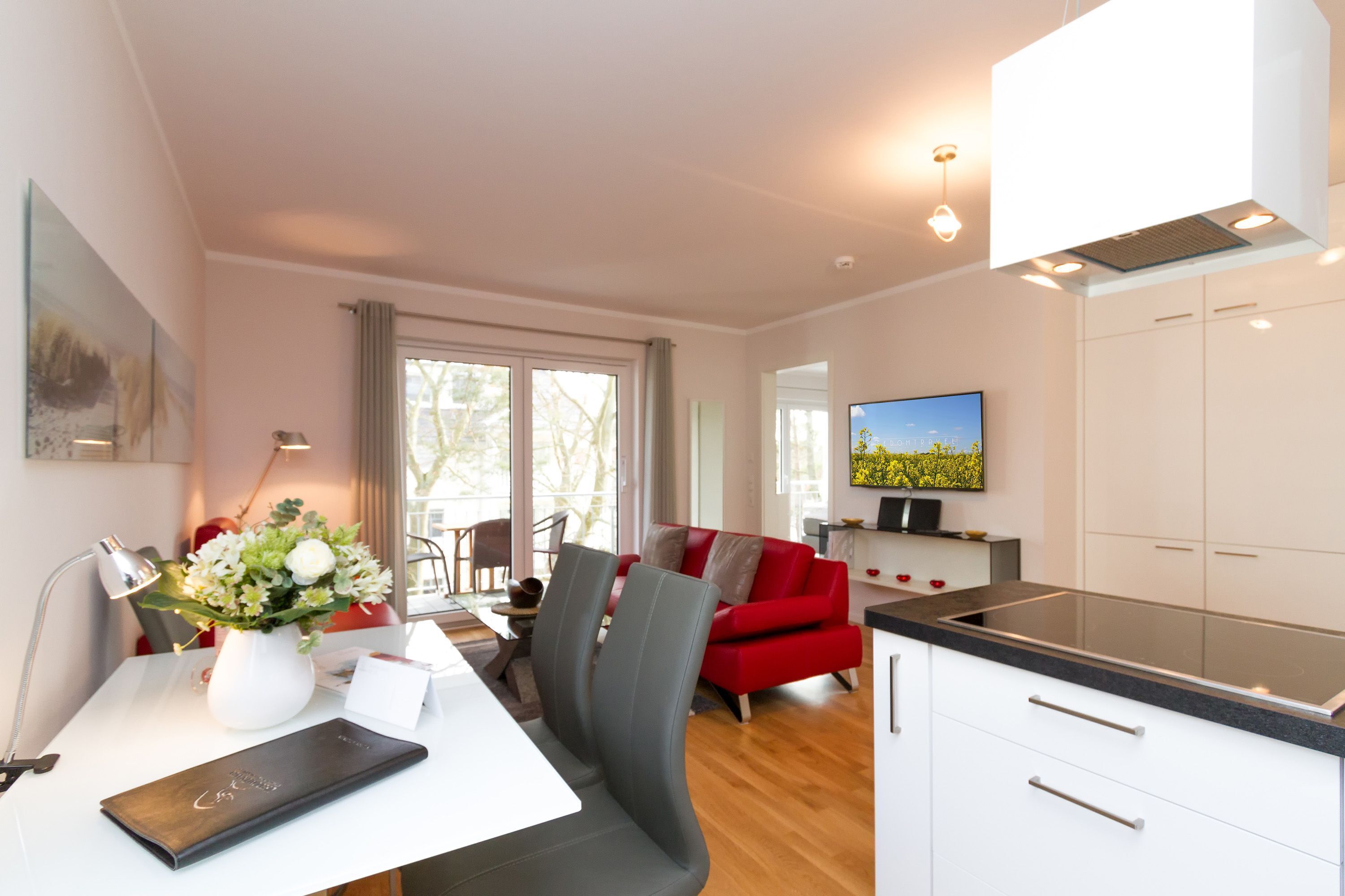 Een moderne keuken met witte kastjes, een zwart aanrecht en een eethoek met een witte tafel en stoelen.