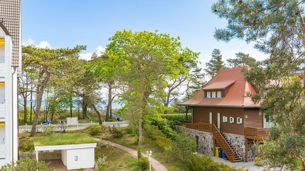 A building with a red roof, stone walls, and a wooden staircase leading to a deck. - Dune Residence Heringsdorf, App. 18 (Heringsdorf)