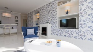 Ein modernes Wohnzimmer mit einem blauen Sofa, einem weißen Couchtisch und einem Fernseher an der Wand.