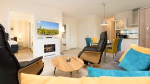 Ein modernes Wohnzimmer mit Kamin, Fernseher und Essbereich mit Stühlen.