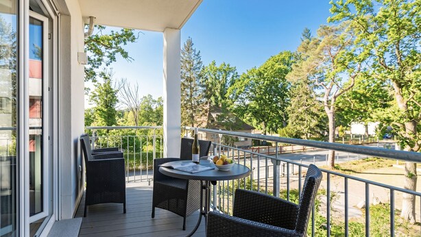 A balcony with a table, chairs, and a bowl of fruit.