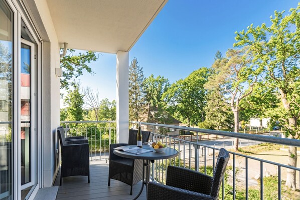 A balcony with a table, chairs, and a bowl of fruit.