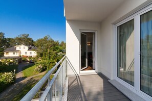 En balkon med udsigt over et boligområde, en dør der fører ind, og en klar himmel.