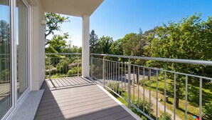 A balcony with a view of a green park and a clear blue sky.