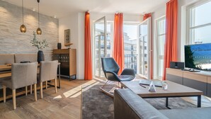 Ein modernes Wohnzimmer mit einer Couch, einem Esstisch, Stühlen und einem Fernseher.