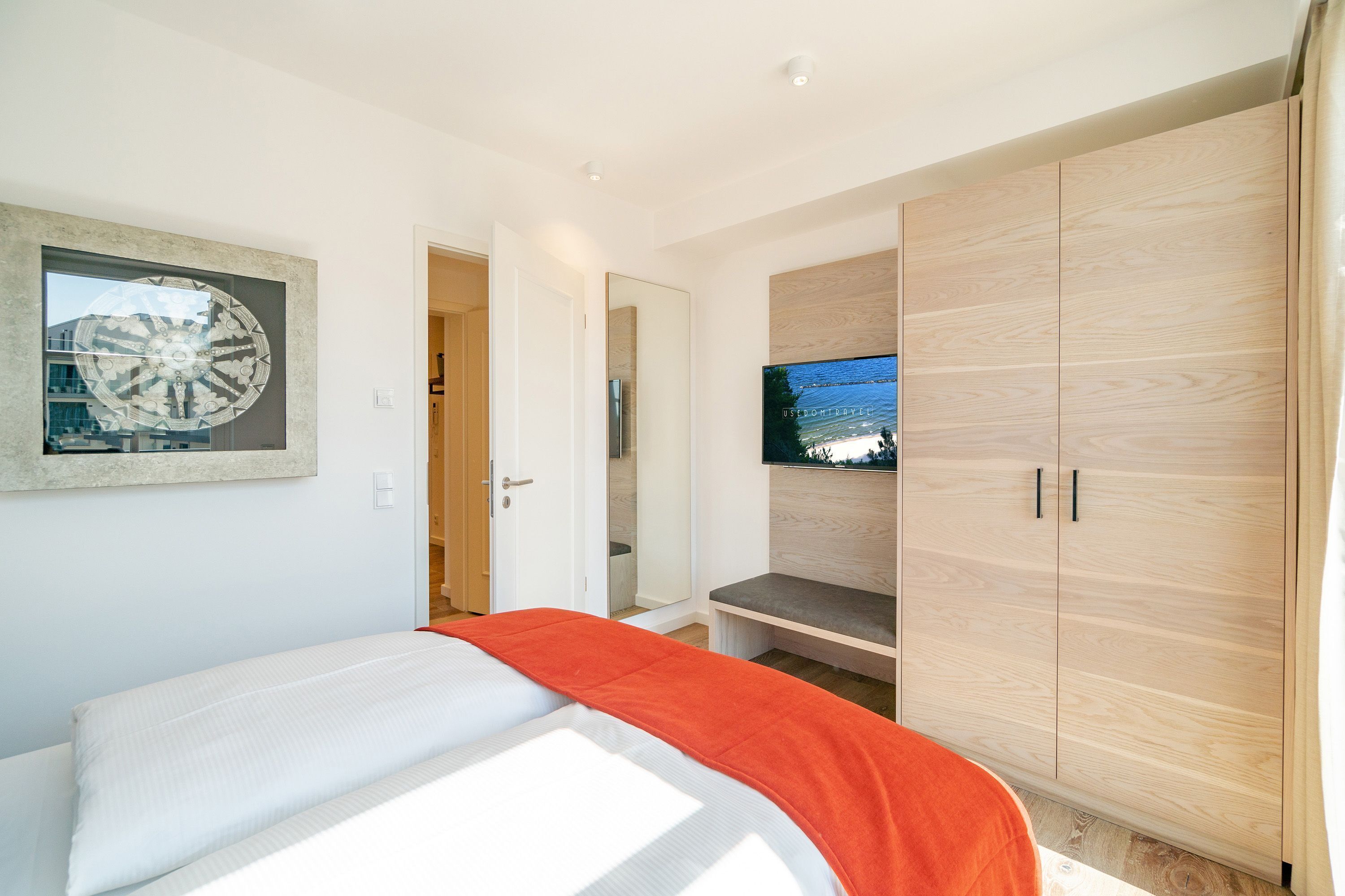 A bedroom with a bed, a TV mounted on the wall, and a wardrobe.