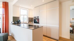 Eine moderne Küche mit einer zentralen Kochinsel, integrierten Geräten und einem großen Fenster.