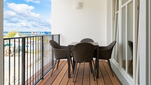 A balcony with a table and chairs, a railing, and a view of the sea and flags. - Beachhouse Bansin, App. 16 (Heringsdorf)