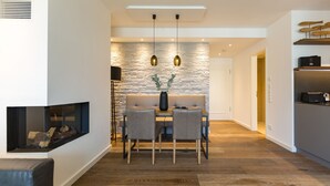 A modern dining area with a stone wall, two pendant lights, and a fireplace. - Beachhouse Bansin, App. 16 (Heringsdorf)