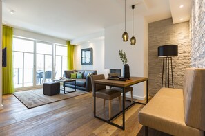 A modern living room with a wooden floor, a dining table, a sofa, and a black floor lamp. - Beachhouse Bansin, App. 16 (Heringsdorf)