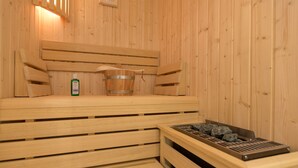 A wooden sauna with benches, a bucket, and a stone tray. - Beachhouse Bansin, App. 16 (Heringsdorf)