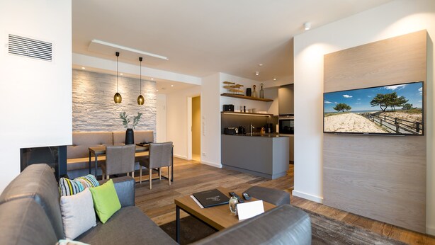 A modern living room with a sofa, coffee table, and a painting of a beach scene. - Beachhouse Bansin, App. 16 (Heringsdorf)