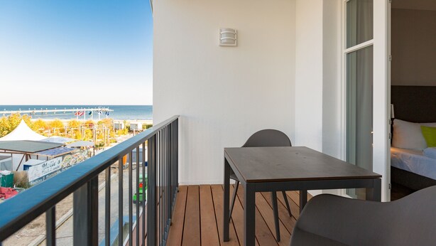 A balcony with a wooden floor, a table, and a chair. - Beachhouse Bansin, App. 17 (Heringsdorf)