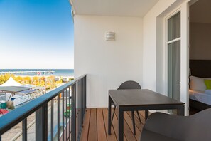 A balcony with a wooden floor, a table, and a chair. - Beachhouse Bansin, App. 17 (Heringsdorf)