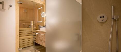 A modern bathroom with a glass shower enclosure, wooden cabinets, and a visible clock.