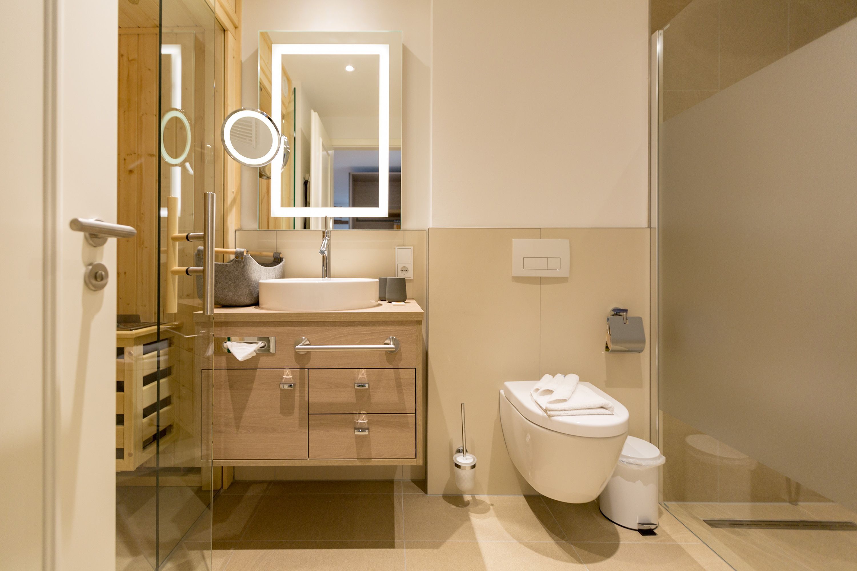 Et moderne badeværelse med brusekabine i glas, et vaskebord med spejl og et toilet.