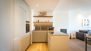 A modern kitchen with a central island, wooden flooring, and a minimalist design. - Beachhouse Bansin, App. 17 (Heringsdorf)