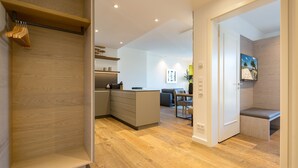 A modern kitchen with built-in appliances, a dining area with a table and chairs, and a living space with a bench. - Beachhouse Bansin, App. 17 (Heringsdorf)