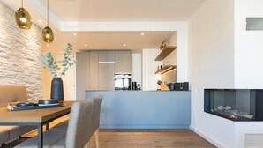 A modern kitchen with a central island, a dining area with a table and chairs, and a fireplace. - Beachhouse Bansin, App. 17 (Heringsdorf)