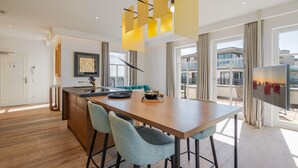 A modern kitchen with a central island, bar stools, pendant lighting, and a view of the city.