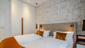 A modern hotel room with a large bed, a wardrobe, and a textured wall.