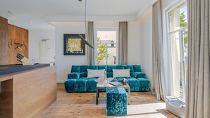 A modern living area with a sofa, ottoman, and a kitchen counter.