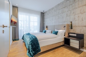 Una habitación de hotel moderna con una cama grande, una mesita de noche, un televisor y vistas a la ciudad.
