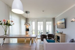 Een moderne woonkamer met een eetgedeelte, een open haard en een balkon met uitzicht.