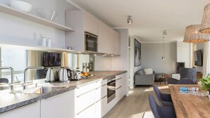Eine moderne Küche mit einer zentralen Kochinsel, eingebauten Geräten und einem Essbereich mit Holztisch und Stühlen.