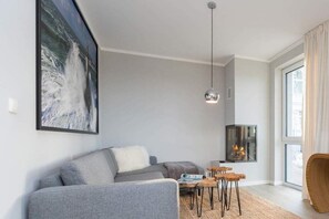 A modern living room with a grey sofa, a coffee table, and a hanging pendant light.
