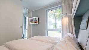 Un dormitorio con dos camas, un ventanal grande y un cuadro en la pared.