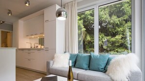 Una sala moderna con un sofá gris, una mesa de centro blanca y una botella de vino.