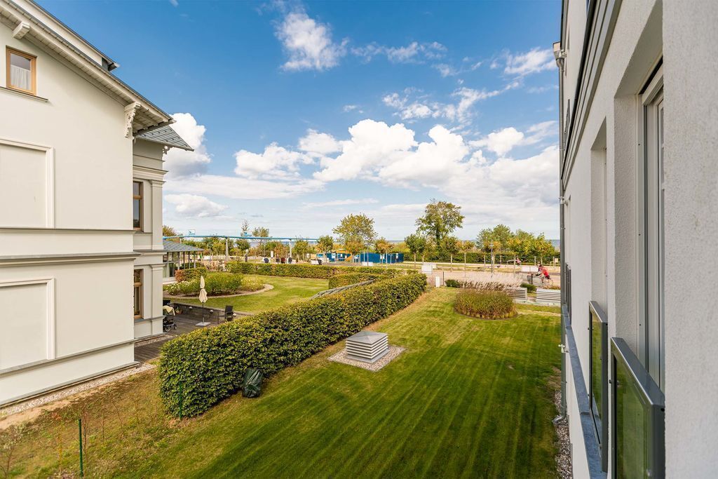 A residential building with a well-maintained lawn, a clear sky, and distant trees.