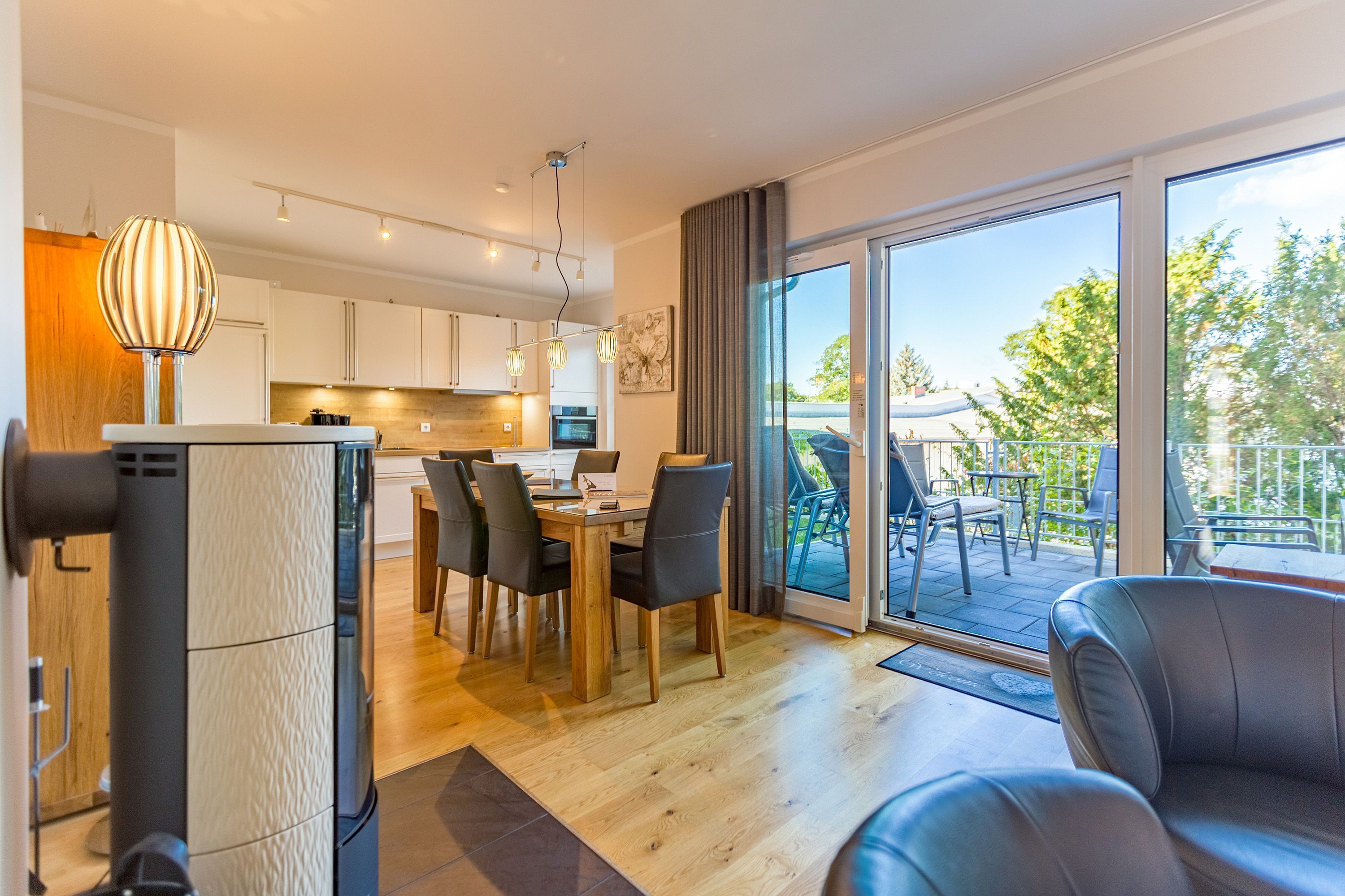 A modern kitchen with a dining area, large sliding glass doors to an outdoor patio, and a seating area with a sofa.
