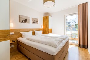 Un dormitorio moderno con una cama grande, cabecera de madera y dos obras de arte colgadas en la pared.