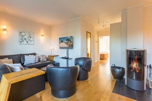 Una sala de estar moderna con un sofá, dos sillones, una mesa de centro, una chimenea y obras de arte en las paredes.