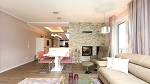 Una sala de estar moderna con un sofá, una mesa de comedor con sillas, una zona de cocina al fondo y una chimenea.