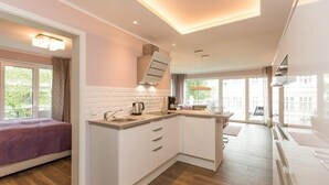 Una cocina moderna con armarios blancos, horno empotrado y un ventanal grande.