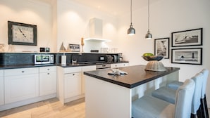 Una cocina moderna con armarios blancos, encimera negra y una isla central.