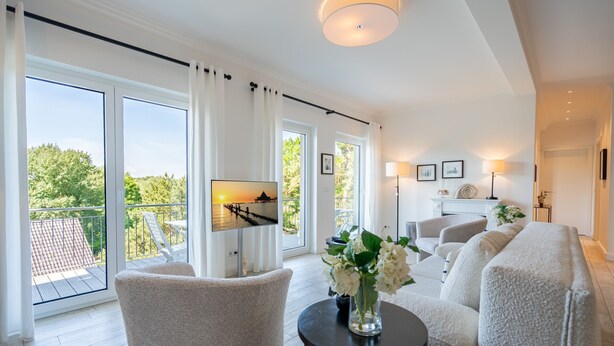 Una sala de estar moderna con sofá, sillas, televisor y un balcón con vistas.