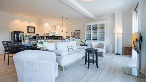 Una sala de estar moderna con sofá, mesa de comedor, sillas y una cocina al fondo.