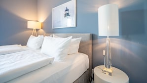 Una habitación de hotel con una cama, una lámpara de noche, un cuadro colgado en la pared y una mesita de noche.