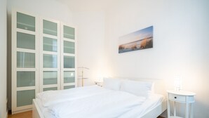 Une chambre à coucher comprenant un lit, une table de chevet, un tableau accroché au mur et une armoire intégrée avec des portes en verre.